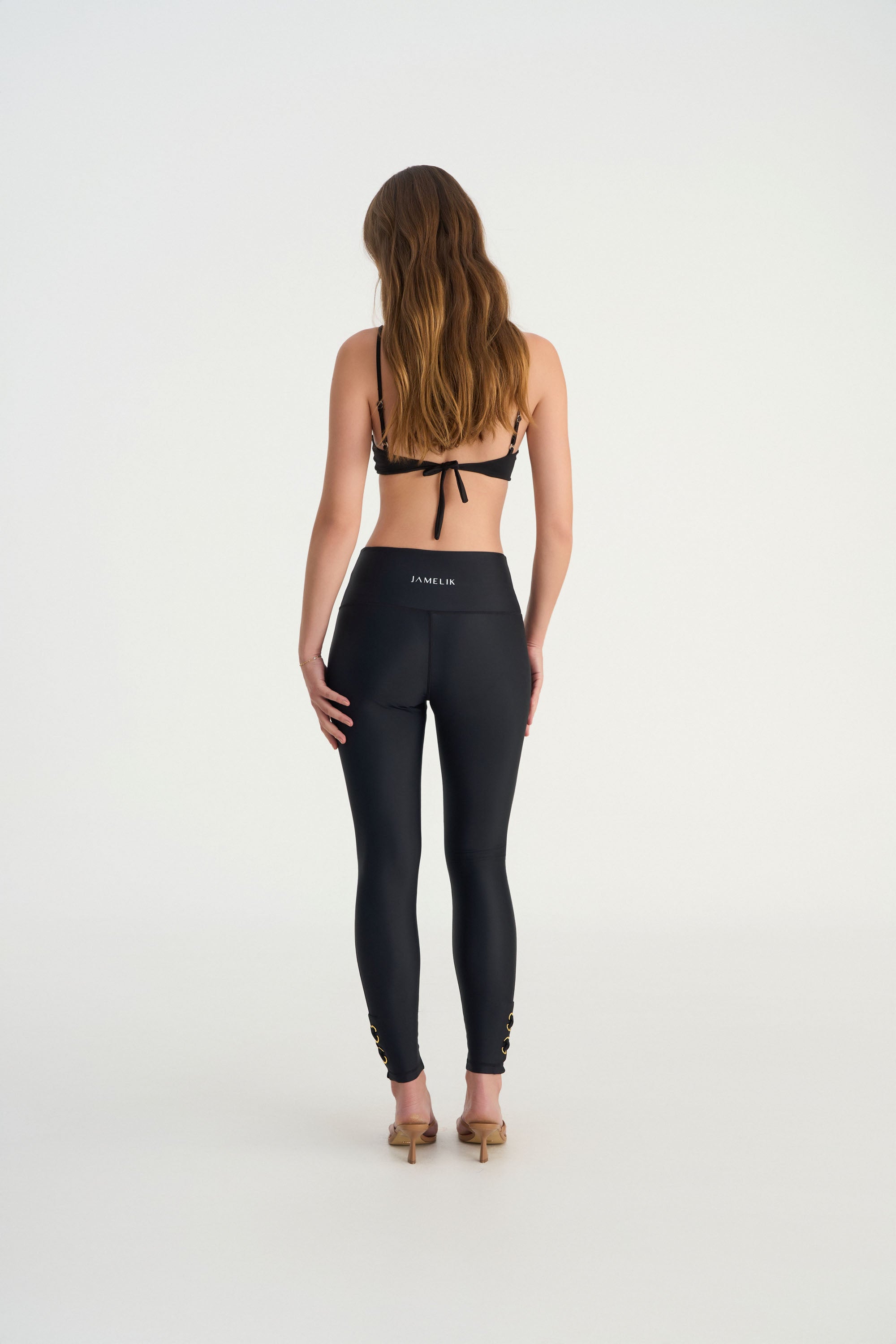 Back view of CEMILE black full coverage swim leggings with sculpting silhouette background with bikini top